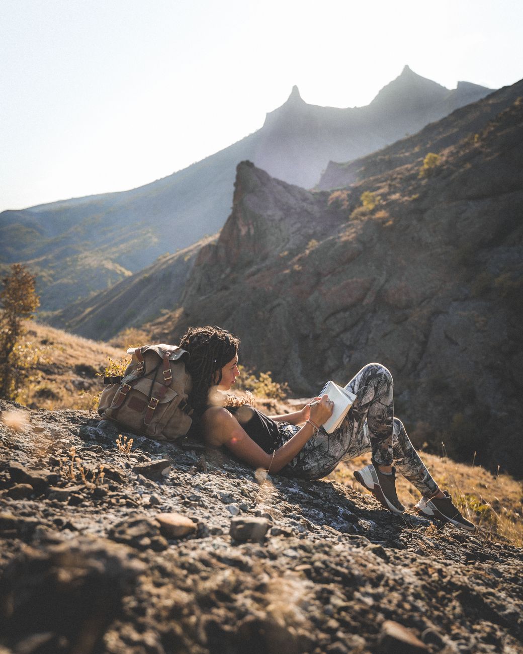 Author reading travel journal overlooking mountain ridge